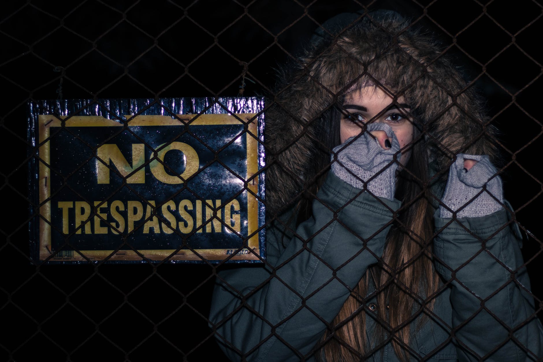 woman behind black chainlink fence with no trespassing signage
